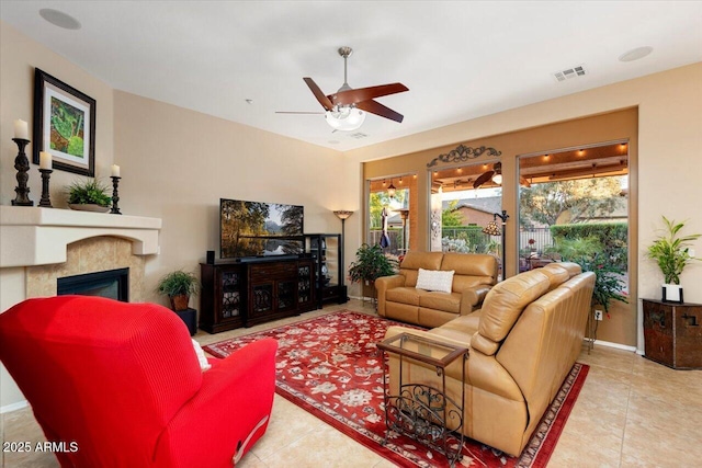 living room featuring a fireplace, ceiling fan, and light tile patterned floors