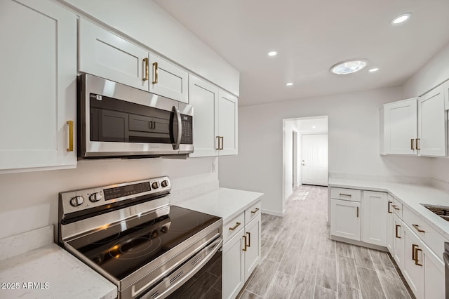 kitchen featuring stainless steel appliances, light stone countertops, and white cabinets