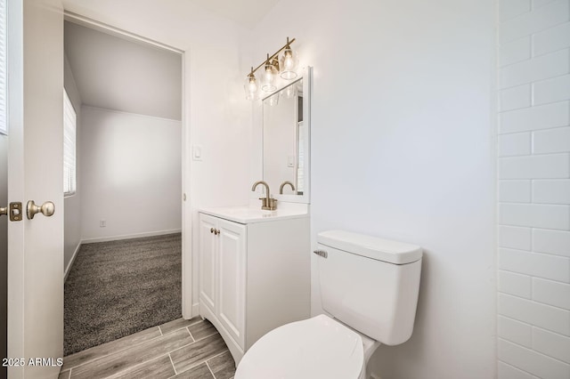 bathroom with toilet, baseboards, vanity, and wood tiled floor