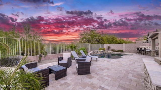 patio terrace at dusk featuring a fenced in pool and a bar