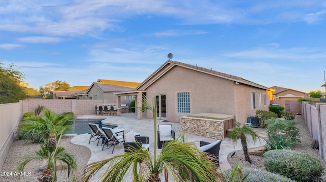 back of property with a hot tub, a bar, and a patio area