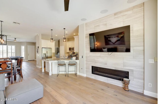 living room with a fireplace, light hardwood / wood-style flooring, and ceiling fan