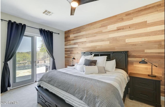 bedroom with access to exterior, wood walls, ceiling fan, and light carpet