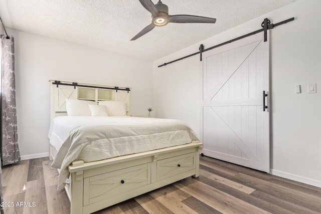 8538 E Portland St, Scottsdale, AZ 85257 - bedroom with a barn door, a textured ceiling, wood finished floors, baseboards, and a ceiling fan