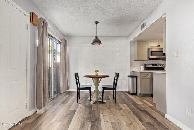 8538 E Portland St, Scottsdale, AZ 85257 - dining area with light wood-type flooring, a textured ceiling, and baseboards
