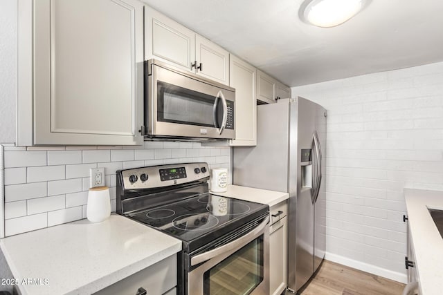 8538 E Portland St, Scottsdale, AZ 85257 - kitchen with stainless steel appliances, light wood finished floors, backsplash, and baseboards
