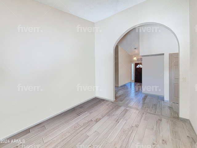 empty room with a textured ceiling and light hardwood / wood-style floors