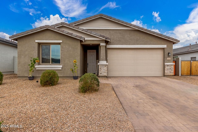 ranch-style house with decorative driveway, an attached garage, fence, and stucco siding