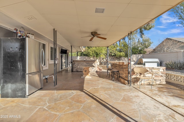 view of patio featuring a bar, ceiling fan, and exterior kitchen