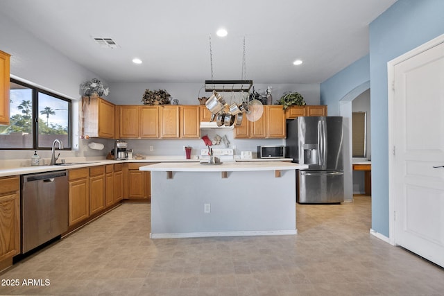 kitchen featuring sink, a kitchen island, range hood, stainless steel appliances, and a kitchen bar