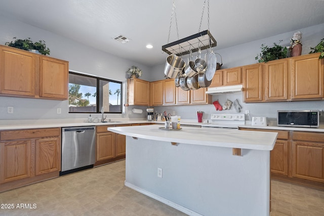 kitchen with a kitchen bar, sink, hanging light fixtures, a kitchen island, and stainless steel appliances