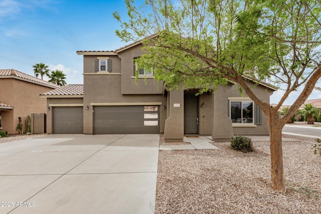 view of front of house with stucco siding, an attached garage, a tiled roof, and concrete driveway