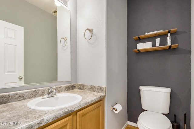 half bath featuring visible vents, toilet, and vanity