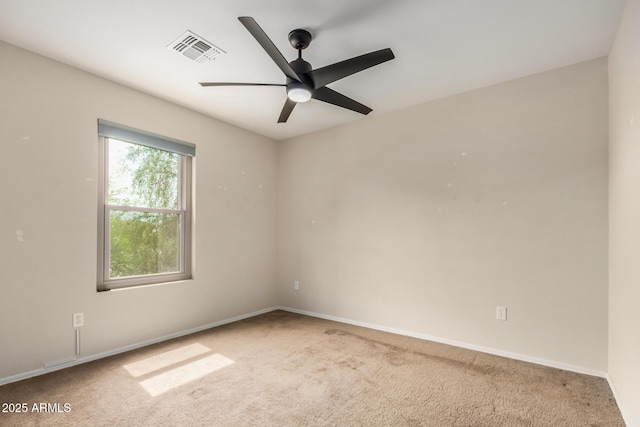 carpeted spare room with baseboards, visible vents, and a ceiling fan