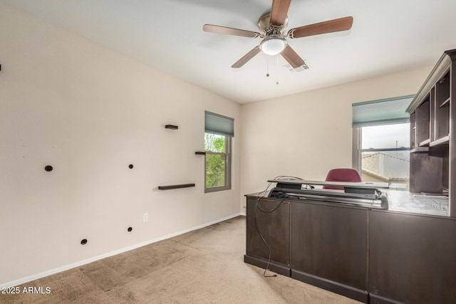 office area featuring light colored carpet, visible vents, a ceiling fan, and a healthy amount of sunlight