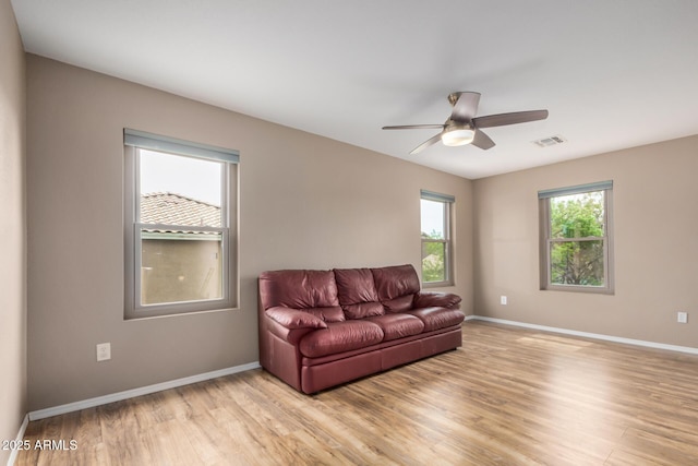 living area with baseboards, visible vents, and light wood-type flooring