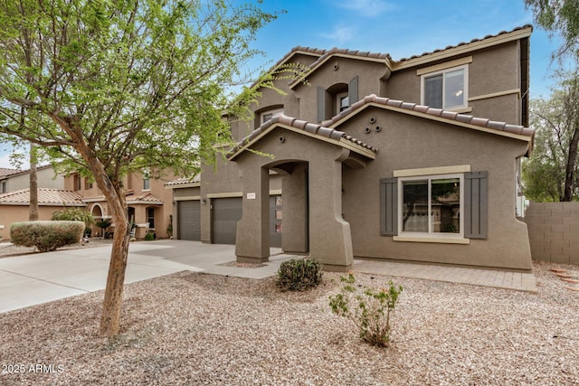 mediterranean / spanish home featuring a tile roof, stucco siding, fence, and concrete driveway