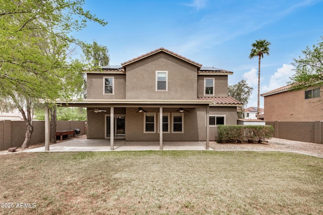 rear view of property featuring stucco siding, a lawn, a ceiling fan, and a patio area