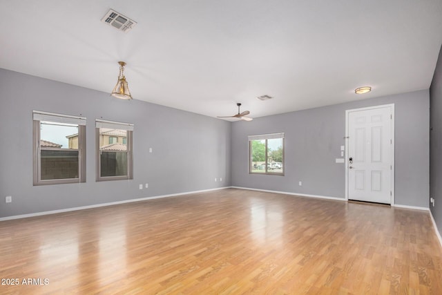 unfurnished living room with light wood-type flooring, baseboards, visible vents, and a ceiling fan