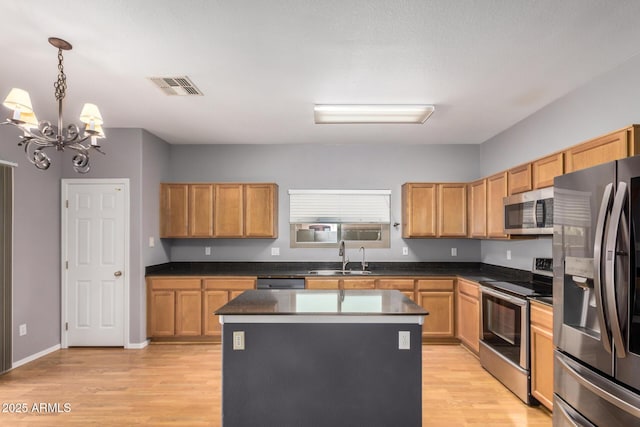 kitchen featuring visible vents, stainless steel appliances, a kitchen island, a sink, and a notable chandelier