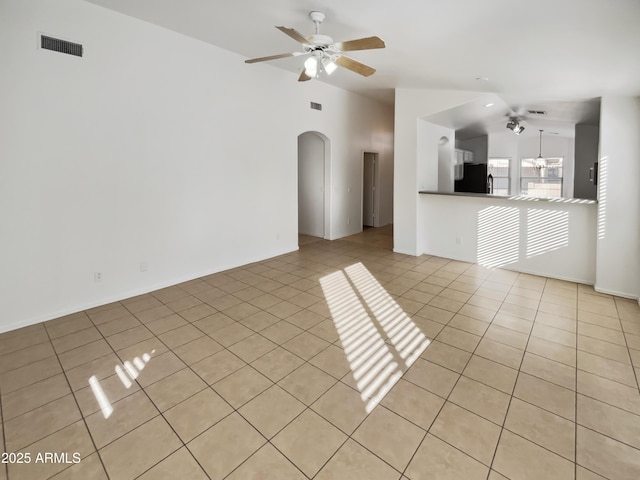 unfurnished living room with ceiling fan, vaulted ceiling, and light tile patterned floors