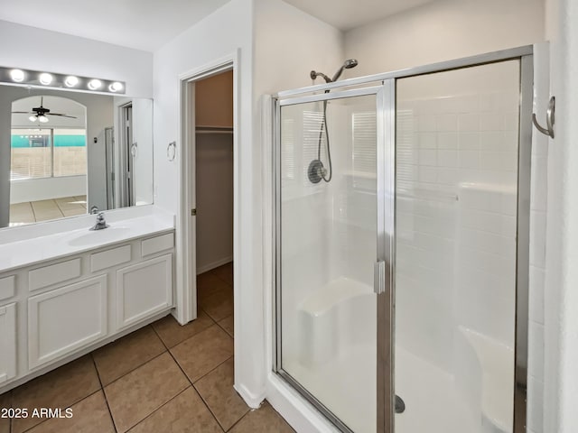 bathroom with tile patterned flooring, vanity, ceiling fan, and walk in shower