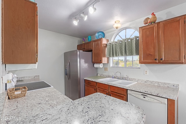 kitchen featuring white dishwasher, sink, rail lighting, stainless steel refrigerator with ice dispenser, and a textured ceiling