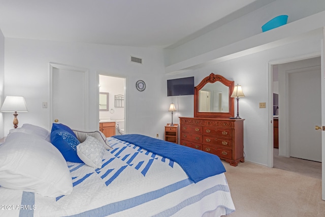 carpeted bedroom with ensuite bathroom and vaulted ceiling