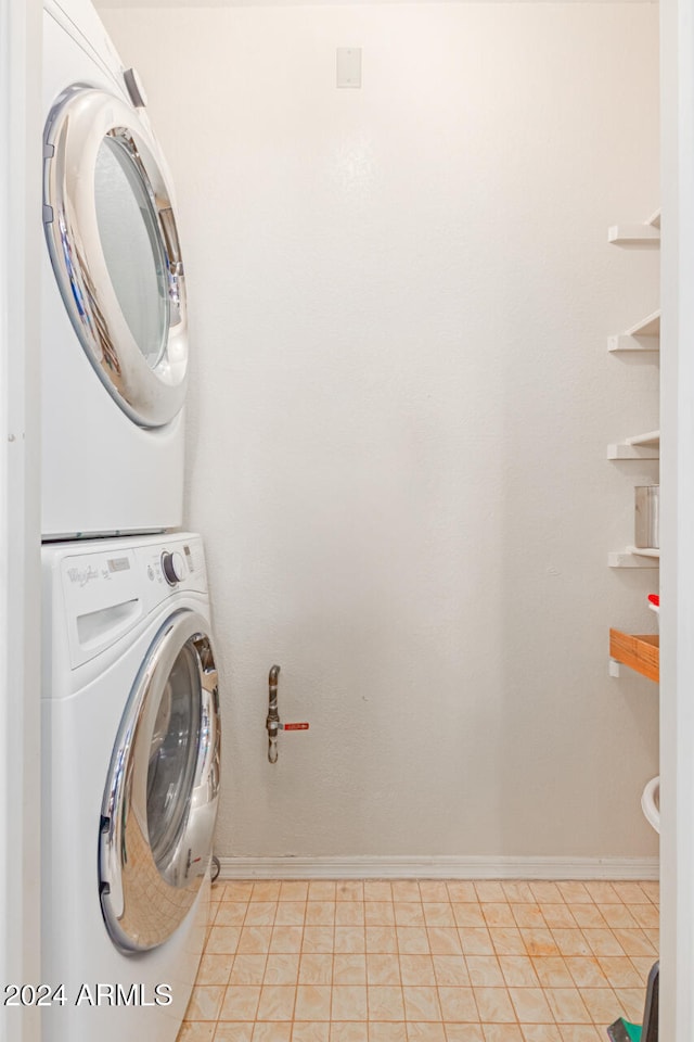 washroom with stacked washer / drying machine and light tile patterned floors