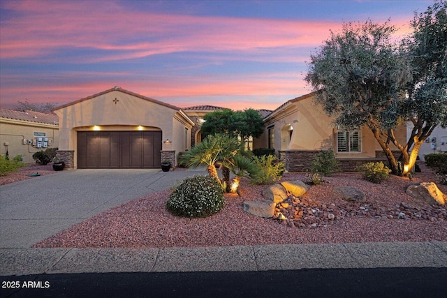 mediterranean / spanish-style home featuring stone siding, driveway, an attached garage, and stucco siding