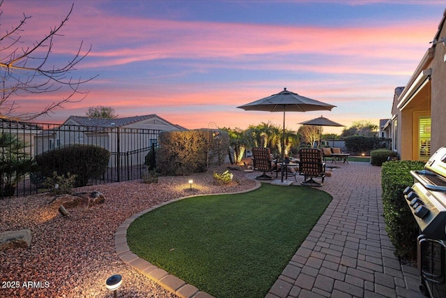 yard at dusk with a patio area and a fenced backyard