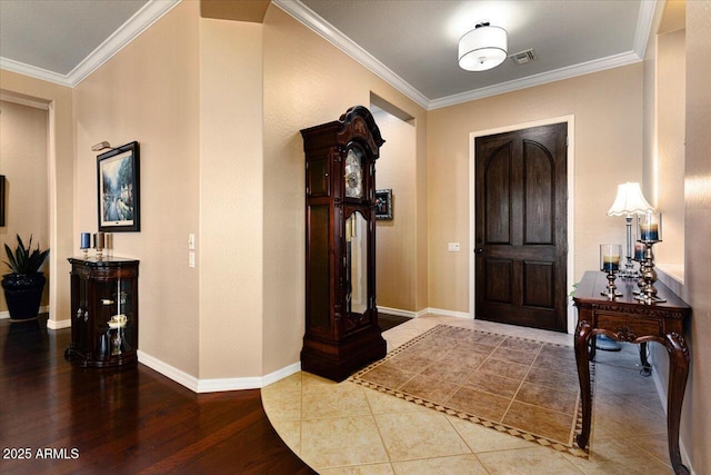 tiled foyer with visible vents, crown molding, and baseboards