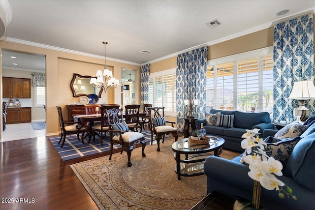 living area with a healthy amount of sunlight, visible vents, crown molding, and wood finished floors