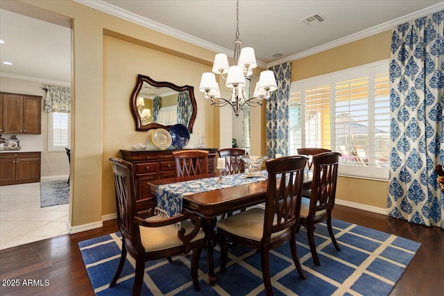 dining space featuring crown molding, a notable chandelier, visible vents, wood finished floors, and baseboards