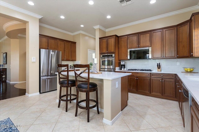 kitchen featuring tasteful backsplash, a kitchen island, stainless steel appliances, crown molding, and light countertops