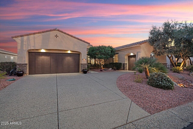 mediterranean / spanish-style house featuring stone siding, a tile roof, driveway, and stucco siding