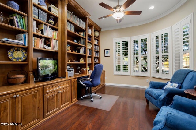 office with ornamental molding, dark wood-type flooring, a ceiling fan, built in study area, and baseboards