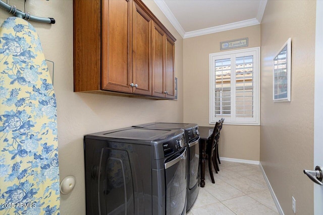 clothes washing area featuring cabinet space, light tile patterned floors, baseboards, ornamental molding, and washing machine and dryer