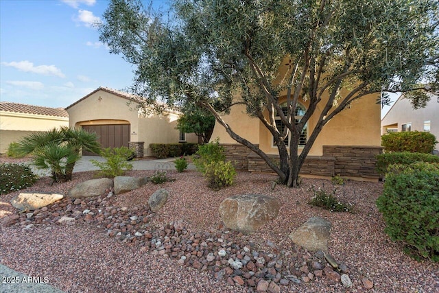 view of front of property with stone siding, a tile roof, and stucco siding