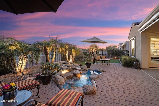 patio terrace at dusk featuring a fenced backyard