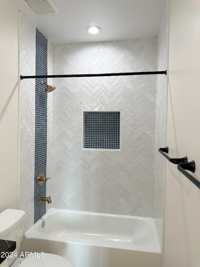 bathroom featuring tiled shower / bath combo and toilet