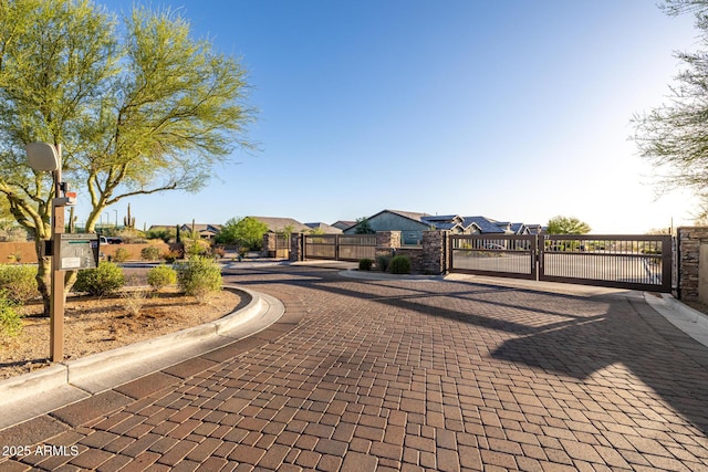 view of decorative street featuring a gate, curbs, a gated entry, and a residential view