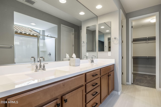 bathroom featuring a shower with door and vanity