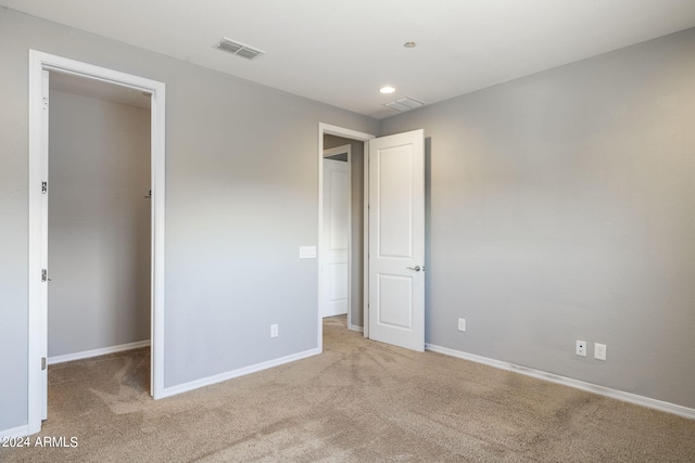 unfurnished bedroom featuring light carpet and a spacious closet