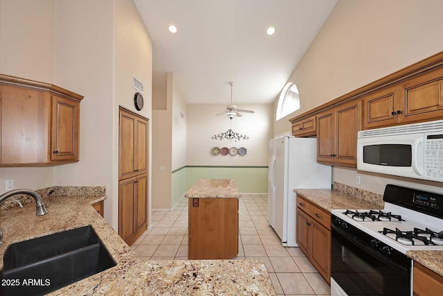 4081 N 156th Dr, Goodyear, AZ 85395 - kitchen featuring white appliances, a sink, brown cabinetry, ceiling fan, and a center island