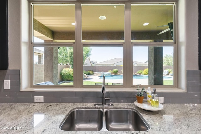 11875 W Lone Tree Trl, Peoria, AZ 85383 - kitchen featuring a sink, decorative backsplash, healthy amount of natural light, and light stone countertops
