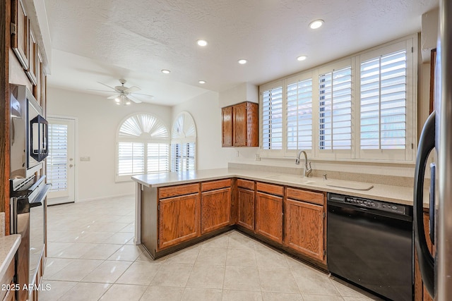 kitchen with light tile patterned floors, sink, stainless steel appliances, a textured ceiling, and kitchen peninsula