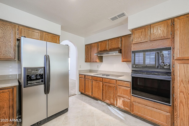 kitchen featuring light tile patterned floors, a textured ceiling, and black appliances