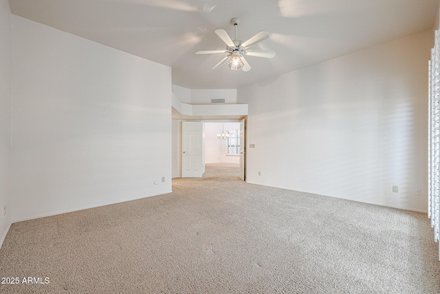 carpeted spare room with ceiling fan with notable chandelier