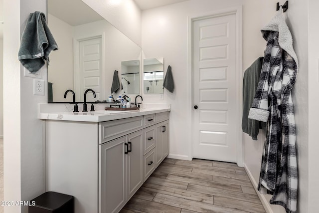 bathroom with baseboards, double vanity, and wood finished floors